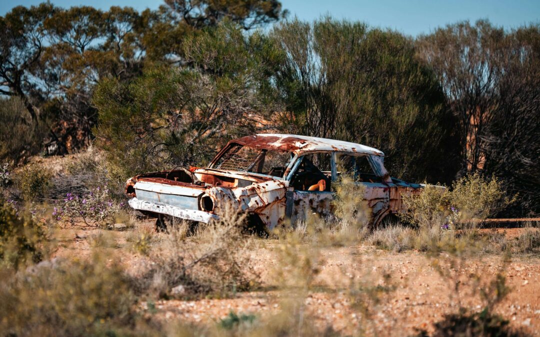 Image of a rusting old car in field waiting to be turned into scrap metal