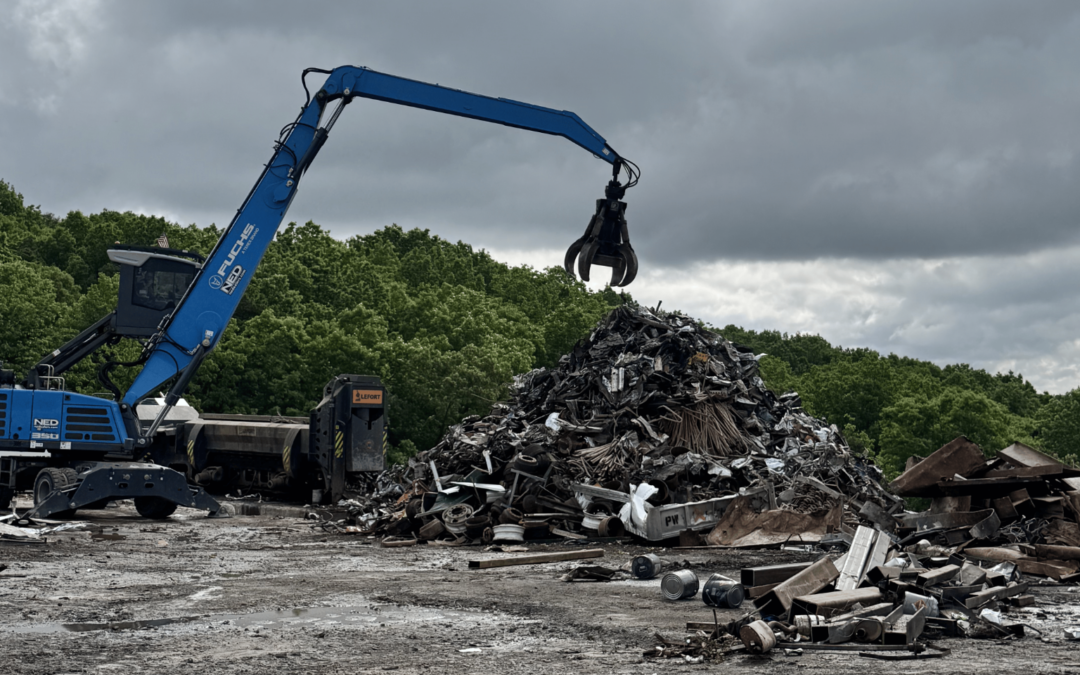 Industrial scrap metal recycling yard with a material handler sorting metal debris.